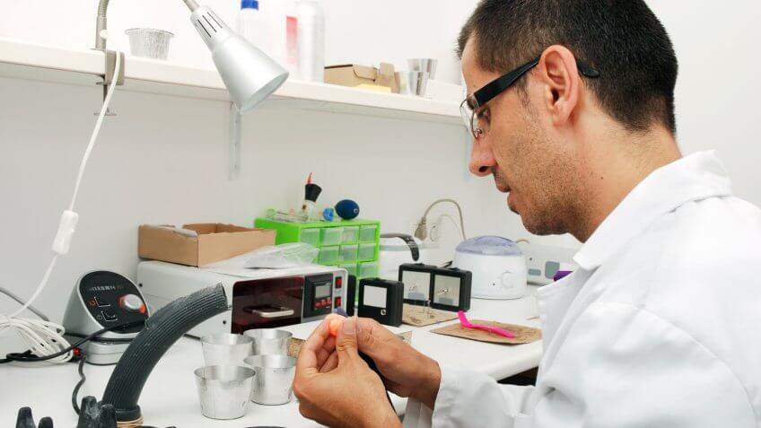 Hearing aid specialist working on custom made ear plugs, used for patients with ears prone to infection through water contact.