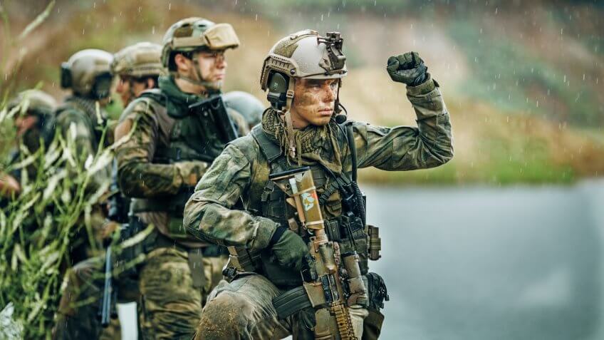 Military squad crossing the river under fire.