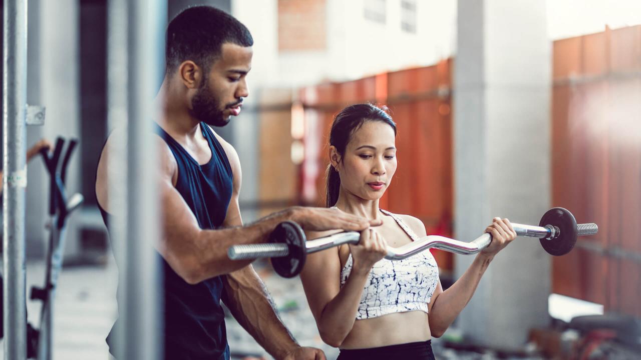 Personal Trainer Coaching a Female Athlete While Lifting Weights.