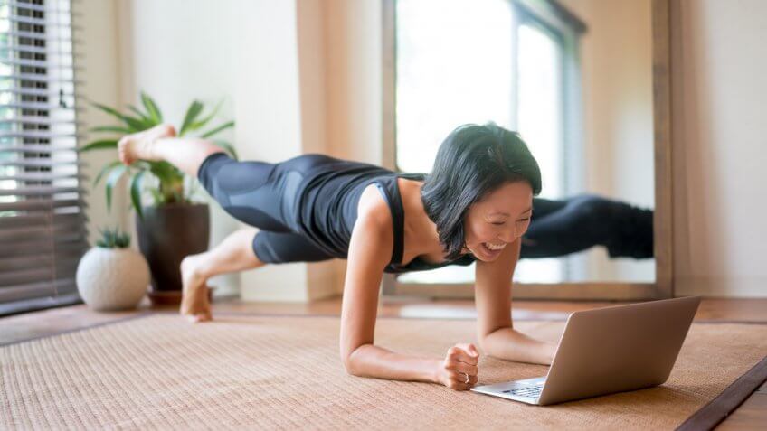 Woman exercising at home following a fitness video online.