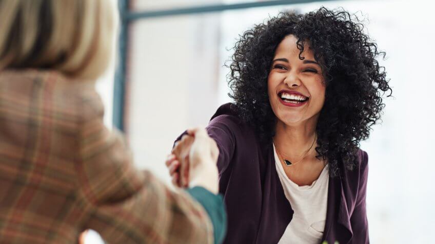 Two colleagues shaking hands during a meeting at work.