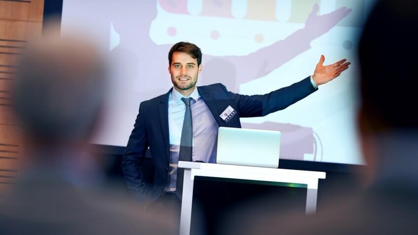 A confident businessman gesturing while giving a presentation at a press conference.