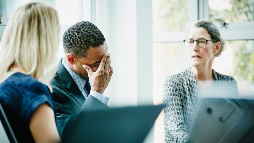 Businessman with head in hand during meeting in office.