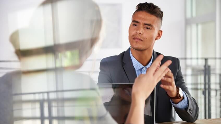 Candid photo of a corporate businesspeople group discussing strategies in professionnal indoors setting.