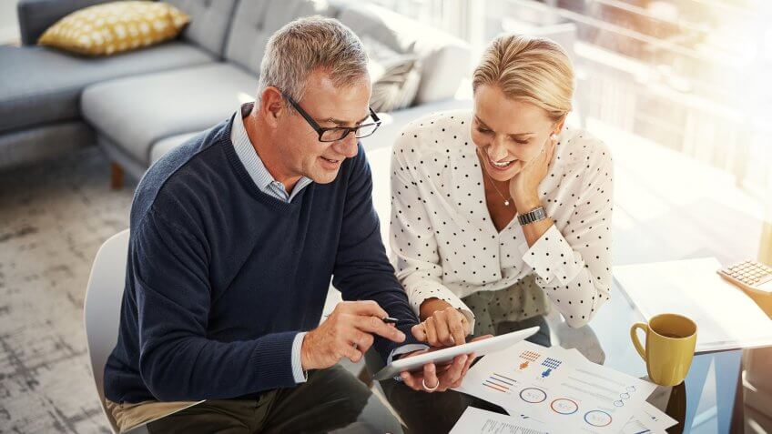 Shot of a mature couple using a digital tablet while going through paperwork at home.