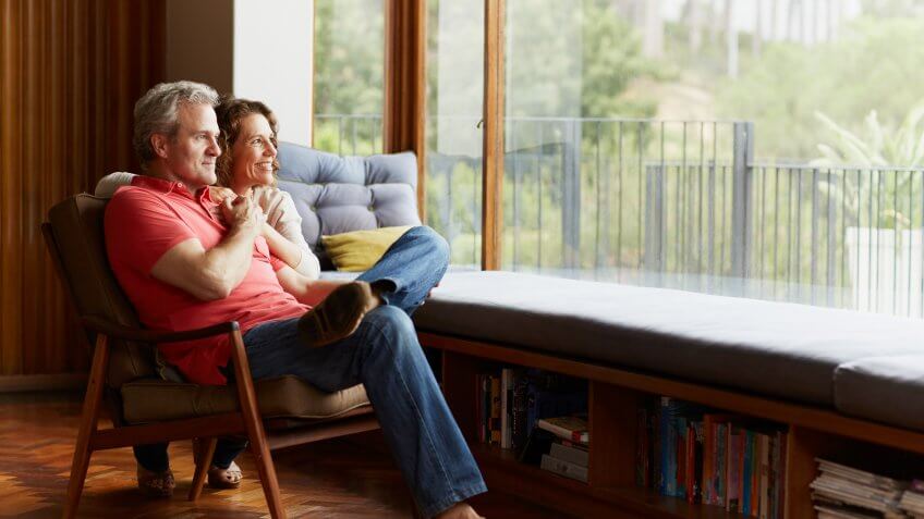 Thoughtful mature couple relaxing by window at home.