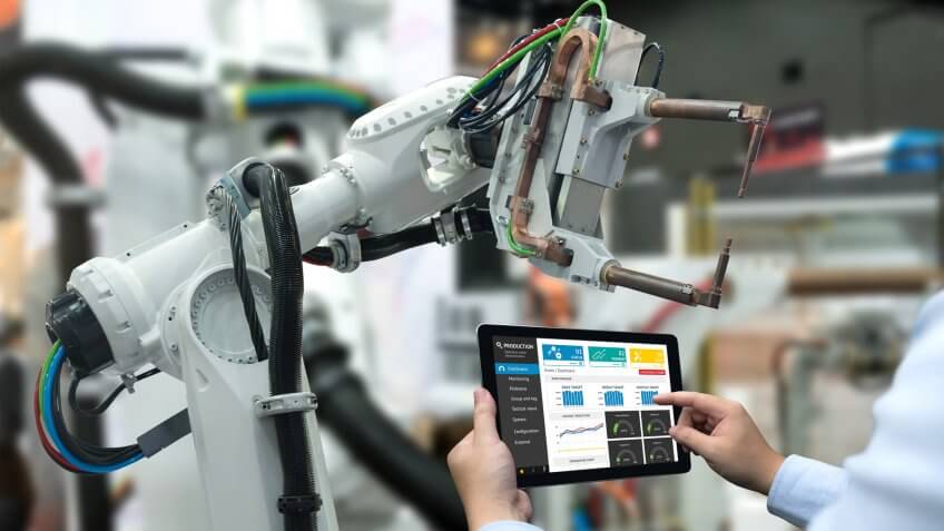 Engineer hand using tablet, heavy automation robot arm machine in smart factory industrial with tablet real time monitoring system application.