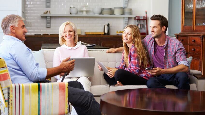 Parents With Adult Offspring Using Digital Devices At Home.