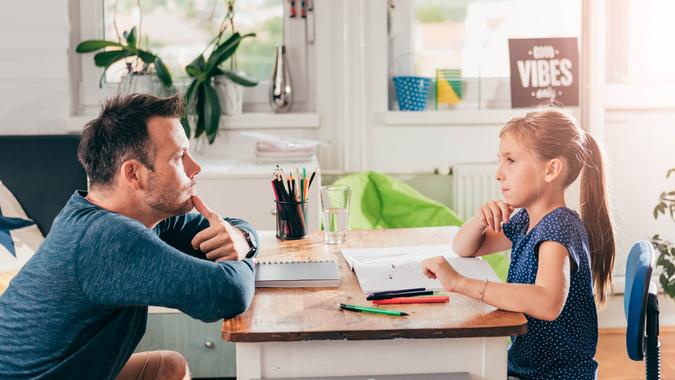 Girl doing homework and contemplating with father.