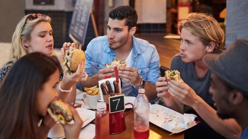 Young male and female friends having burgers in restaurant.