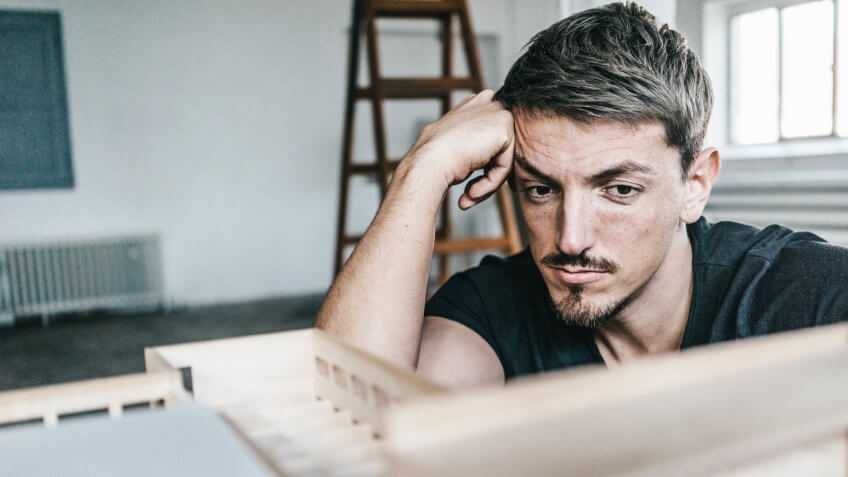 Serious architect looking at architectural model