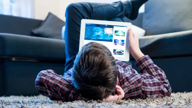 teenager with tablet while lying on the floor in the room.