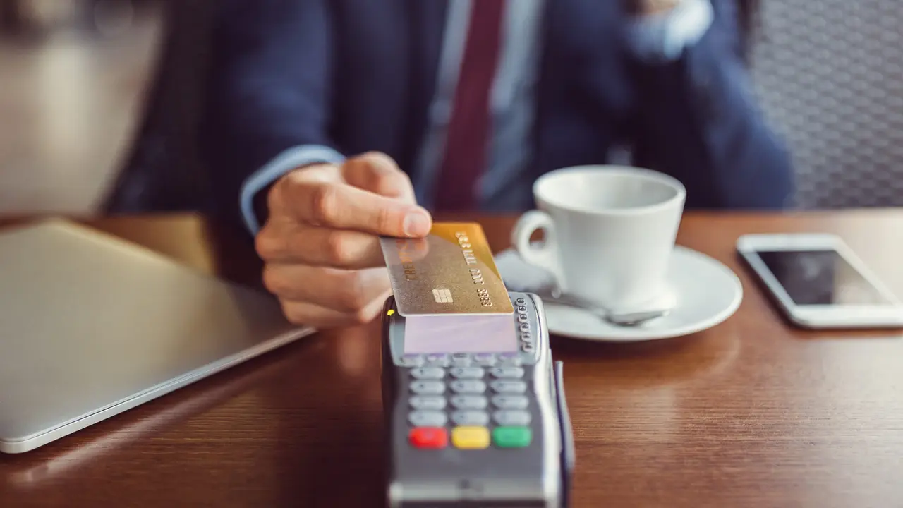 Smiling man at coffee break paying with credit card.