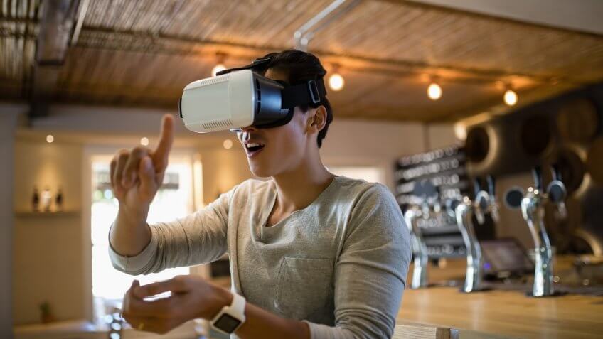 Smiling man using virtual reality headset in restaurant.