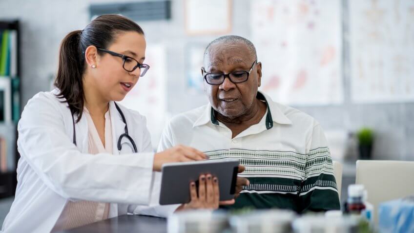 A senior man of African descent is indoors in a hospital room.