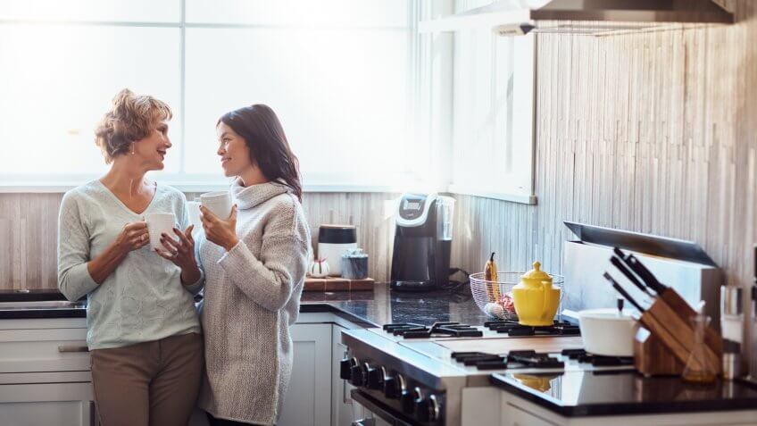 Shot of a young woman enjoying a coffee break and chat in the kitchen with her mother at home.