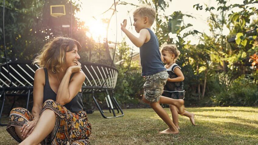 Shot of a young mother hanging outside with her son and daughter.