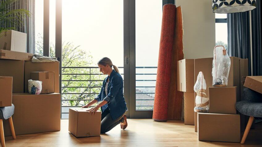 focused middle aged woman packing out a box at her new home inside during the day.