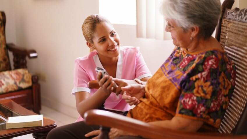 Old people in geriatric hospice: elderly lady having eyesight problems viewing the screen of mobile phone.