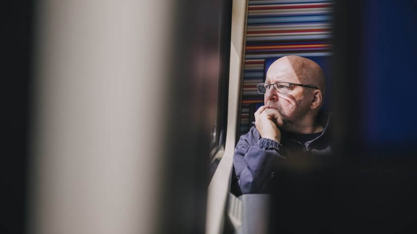 An older man sitting alone on a train in Amsterdam.