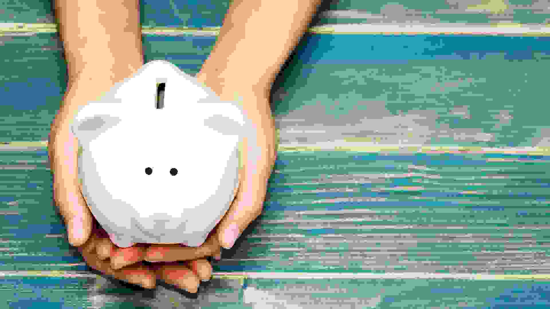 hands holding pig bank on the vintage blue background, a saving money for future investment concept.