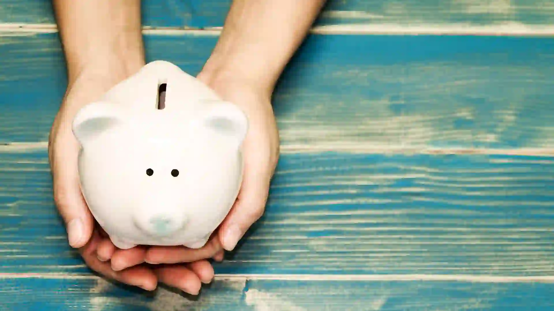 hands holding pig bank on the vintage blue background, a saving money for future investment concept.