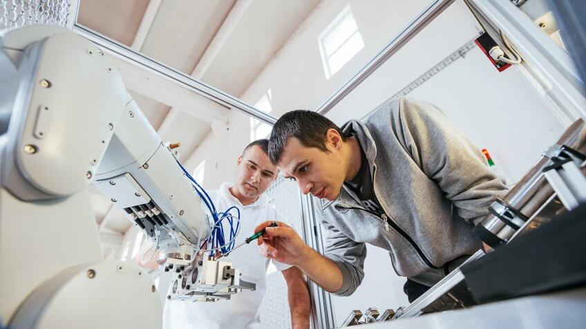 Engineers working on development of automated production line with robotic parts and applied software in order to increase productivity.