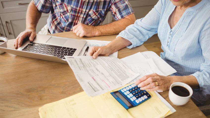 Senior couple checking their bills at home.