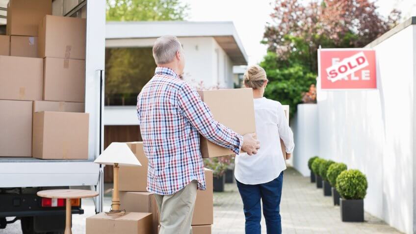 Couple unloading boxes from moving van.
