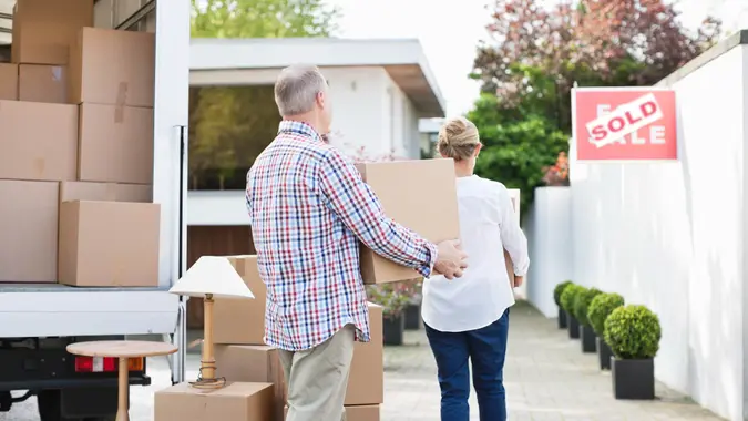 Couple unloading boxes from moving van.