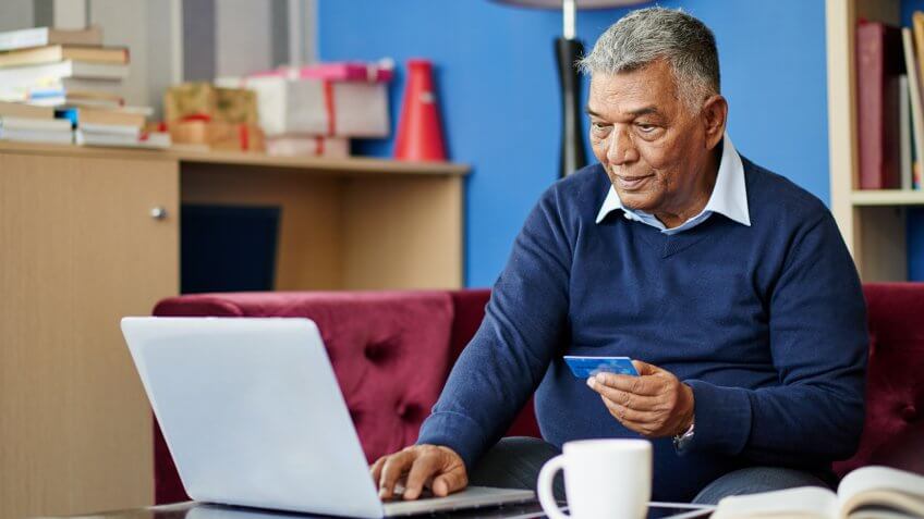 Aged Indian man entering information from his credit card.