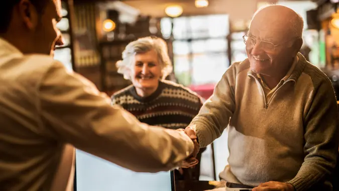 Smiling senior man shaking hands with financial advisor.