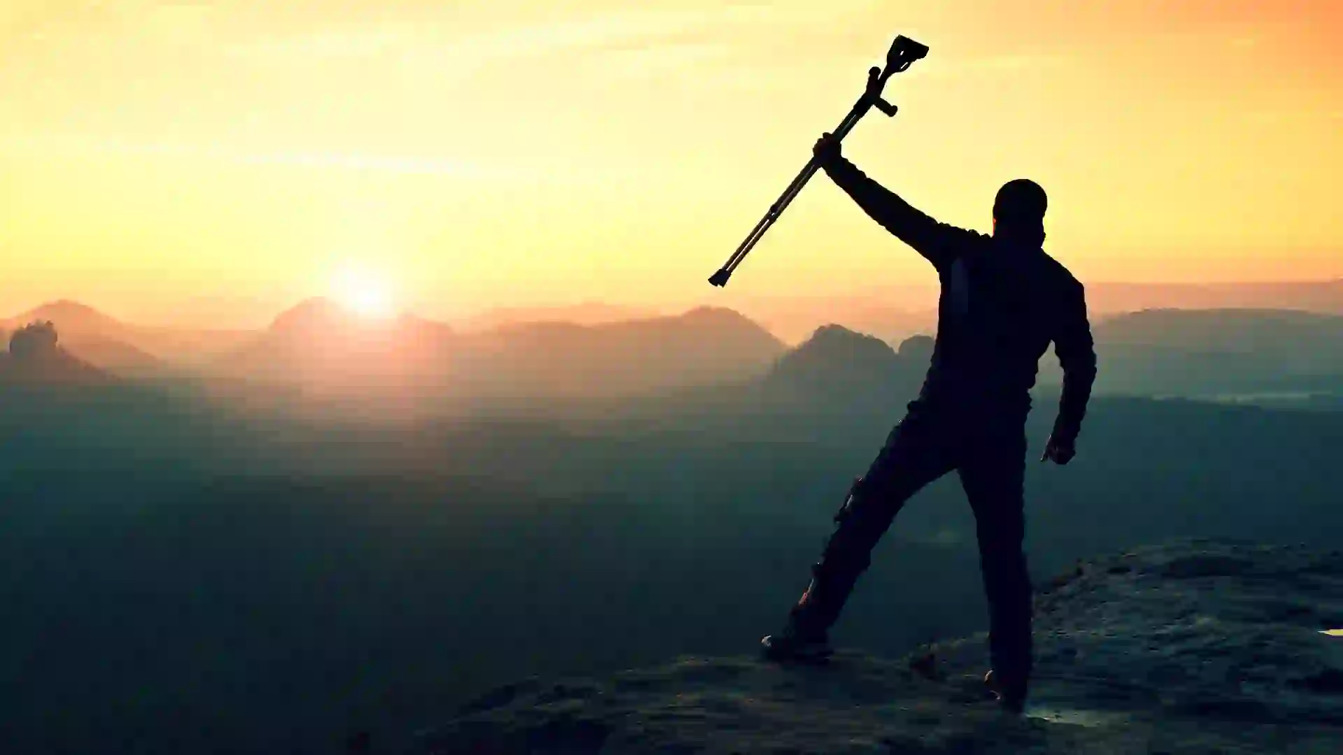 Tourist with forearm crutch above head achieved mountain peak.