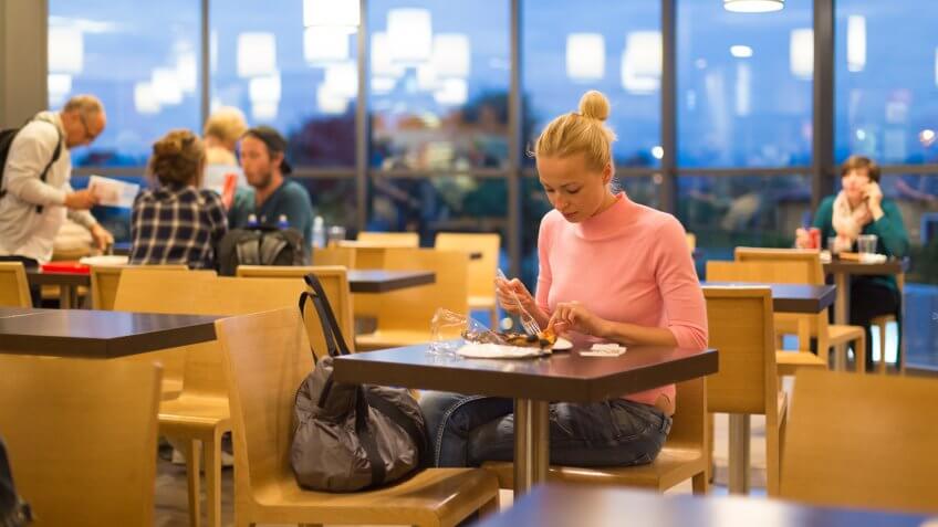 woman eating food in airport cafeteria