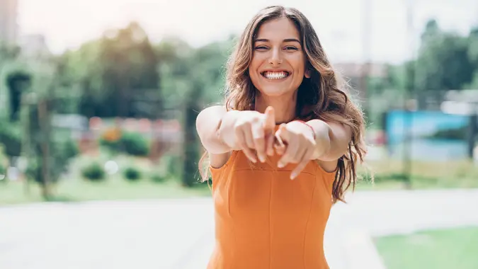 young woman outdoors on a sunny day pointing