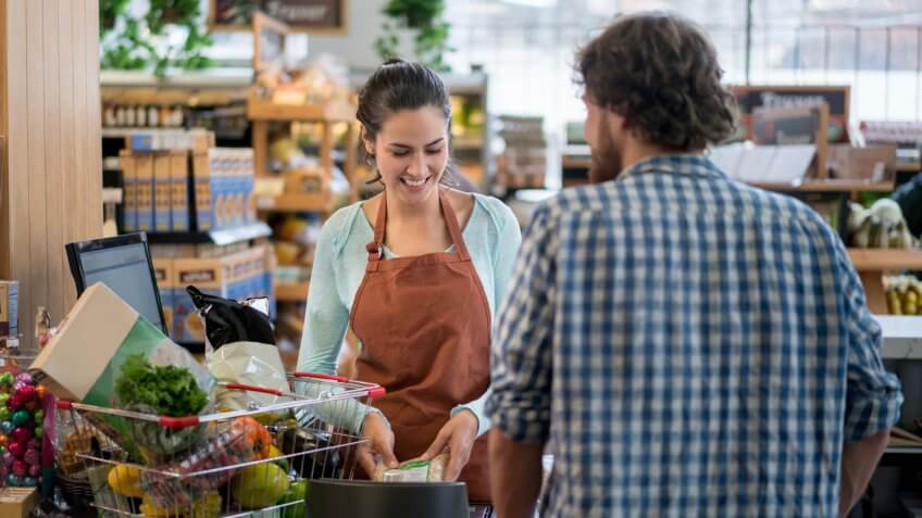Man grocery shopping at the super market and paying at the cashier.