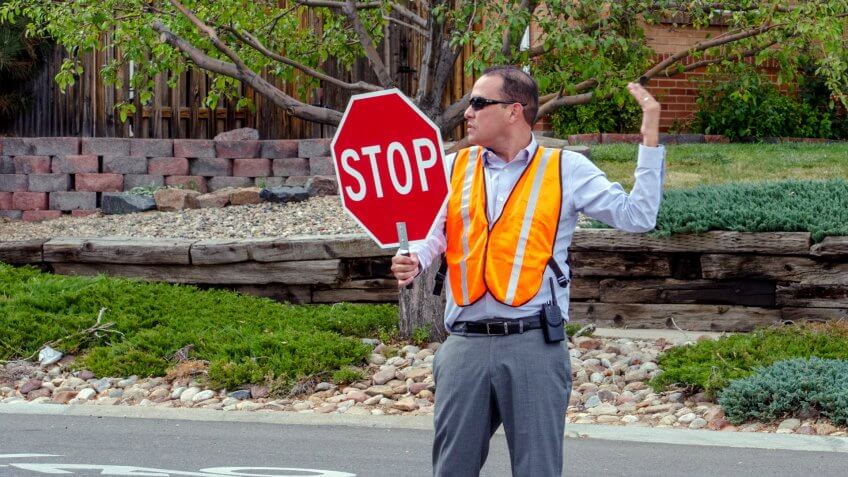 Crossing guard holding a stop sign to pause traffic