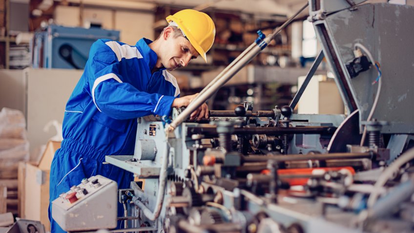 Maintenance engineer or blue collar worker working in production factory, testing and repairing machines, testing roll bars and using grinder or drill.