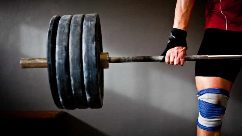 man lifting barbell and disks