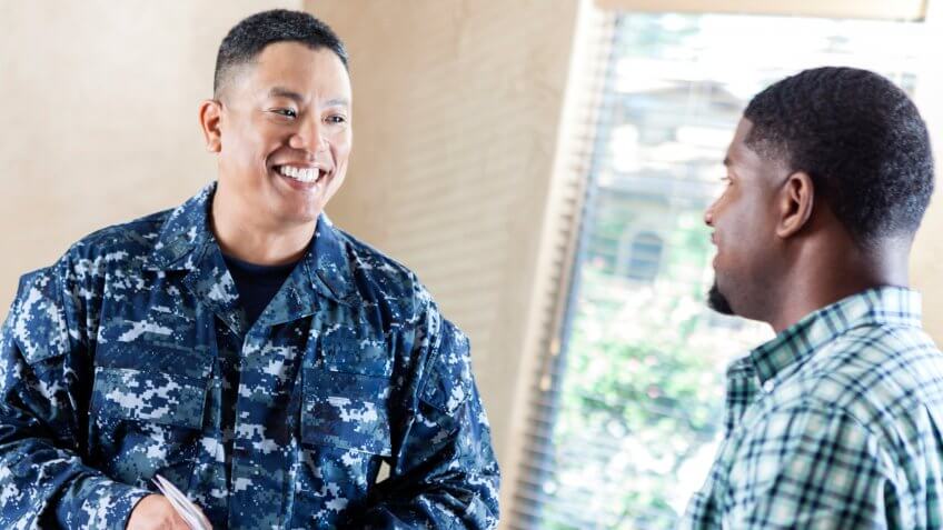Mature adult Asian male soldier is smiling while working at military recruitment event.