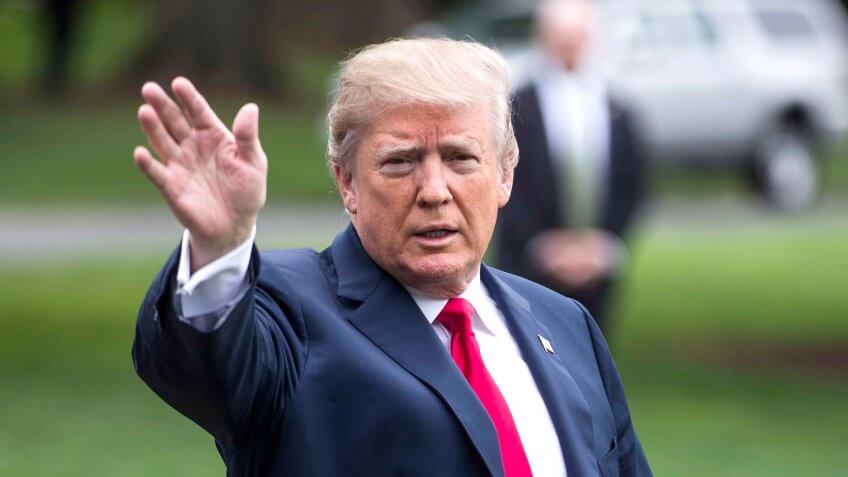 President Donald Trump waves to cameras from lawn