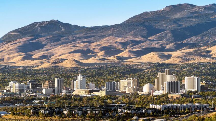 City of Reno Nevada cityscape in early autumn with hotels, casinos, apartments and mountains in the background.
