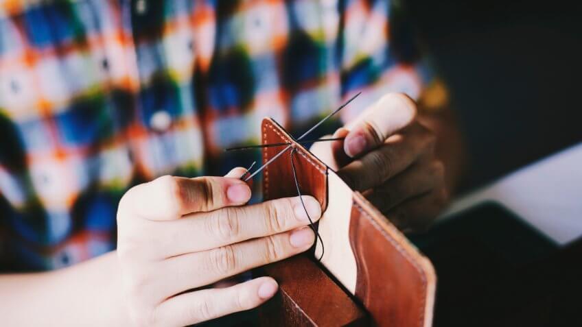 Person sewing together a wallet