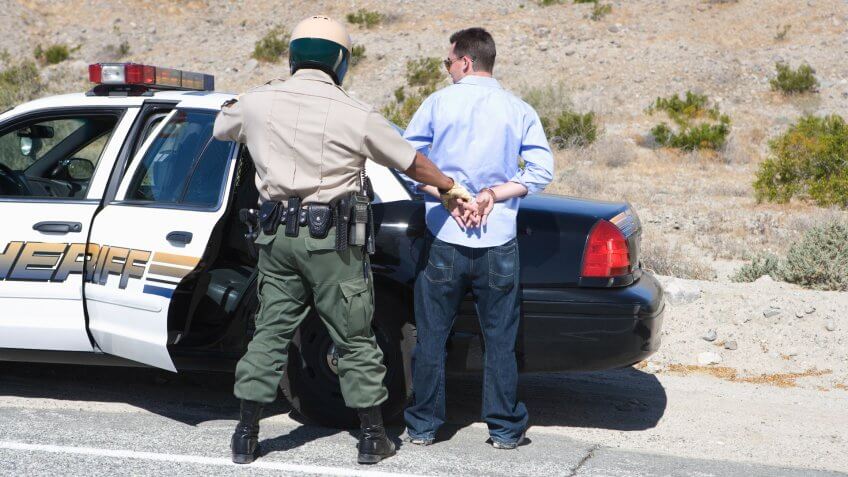 Policeman arresting criminal on road.