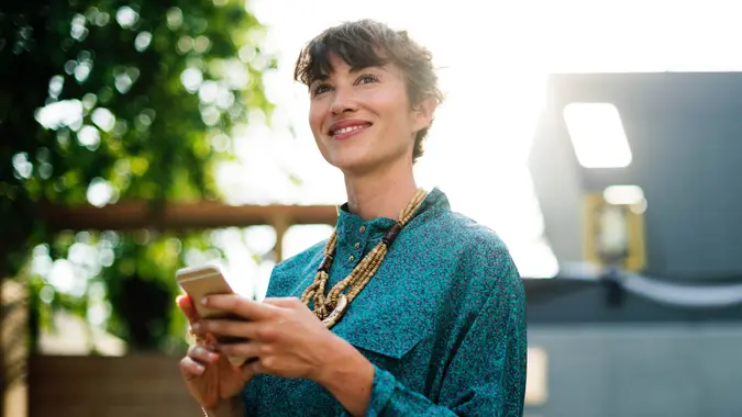 Woman with smartphone smiling while looking up