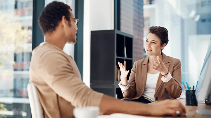 two businesspeople having a discussion in an office.