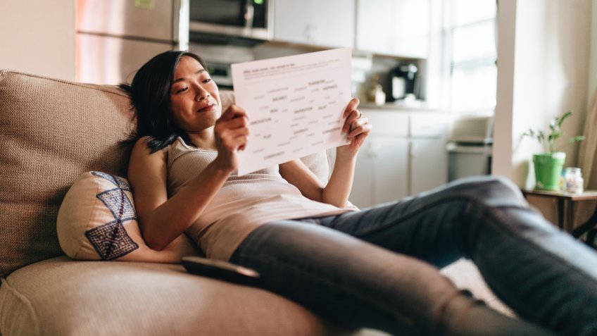 woman reading the papers at home on the couch.