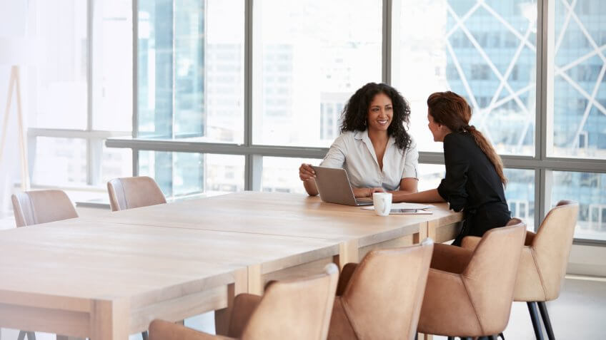 Two Businesswomen Using Laptop In Boardroom Meeting.