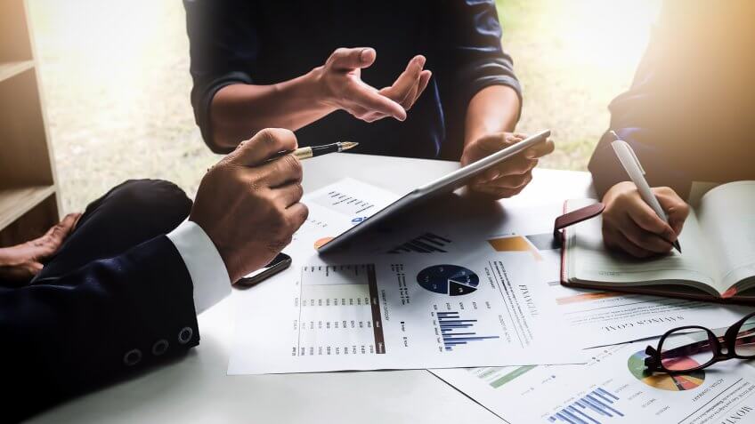 Business people using pen,tablet,notebook are planning a marketing plan to improve the quality of their sales in the future.