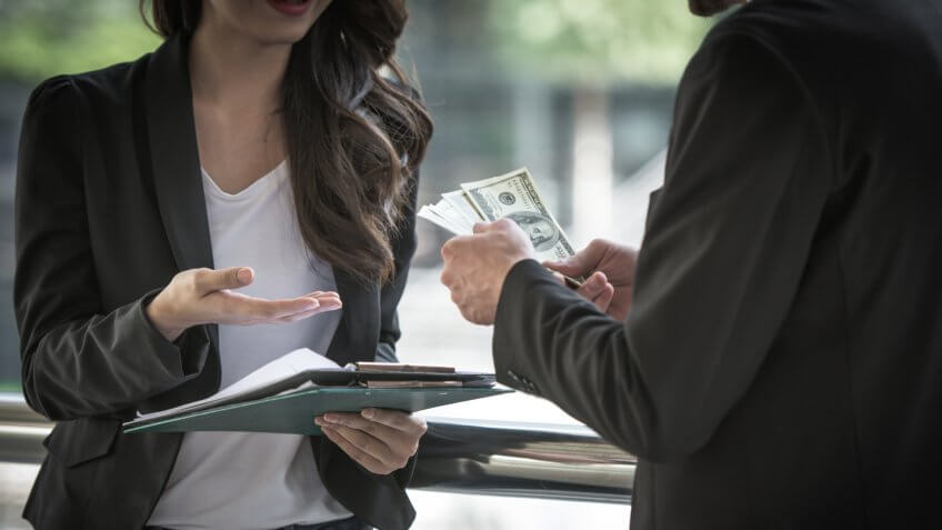 Businessman as an employer paying cash in US dollar bills, wage, loan and bribery concepts.